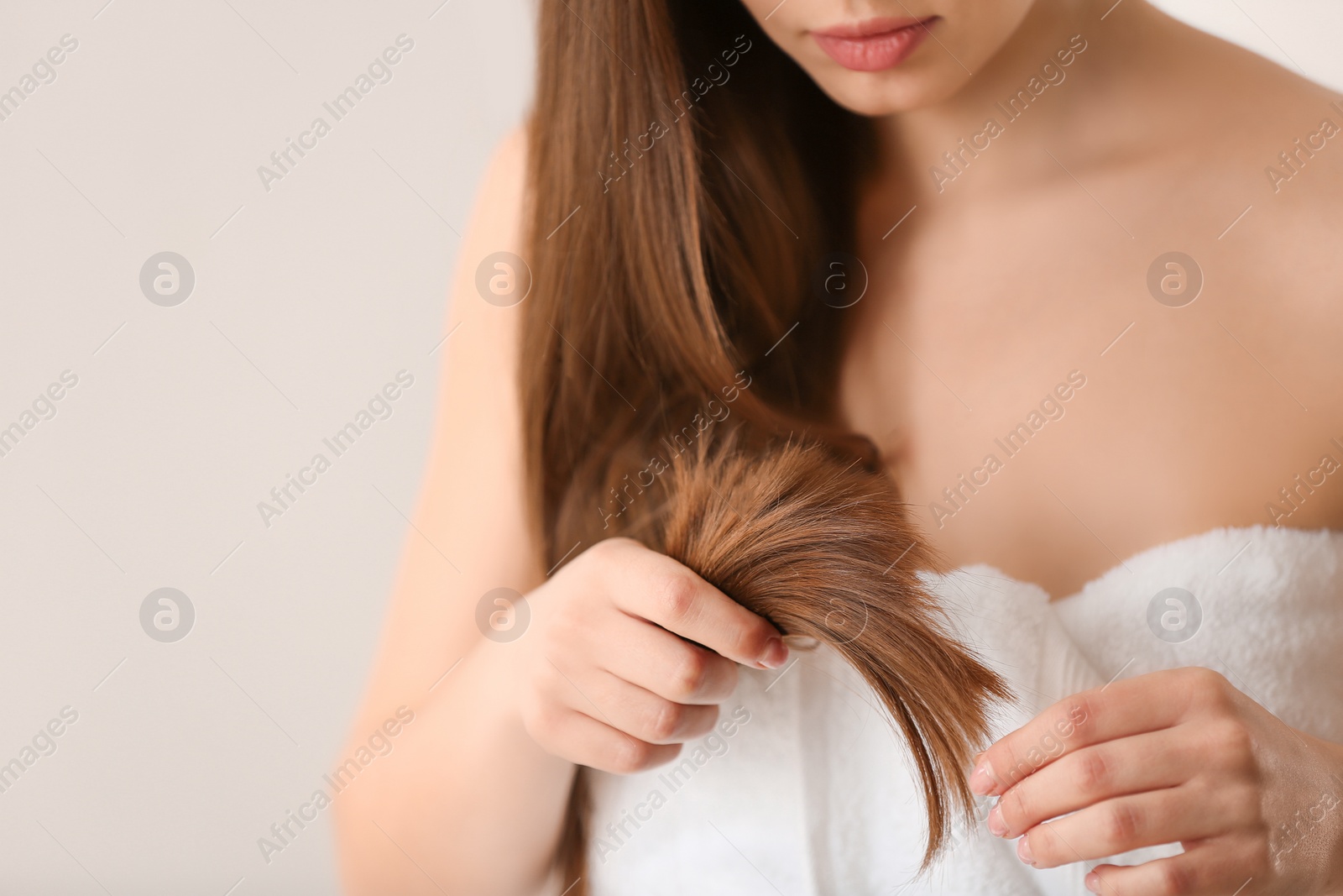 Photo of Woman with damaged hair on light background, closeup. Split ends