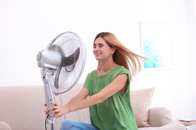 Woman refreshing from heat in front of fan at home