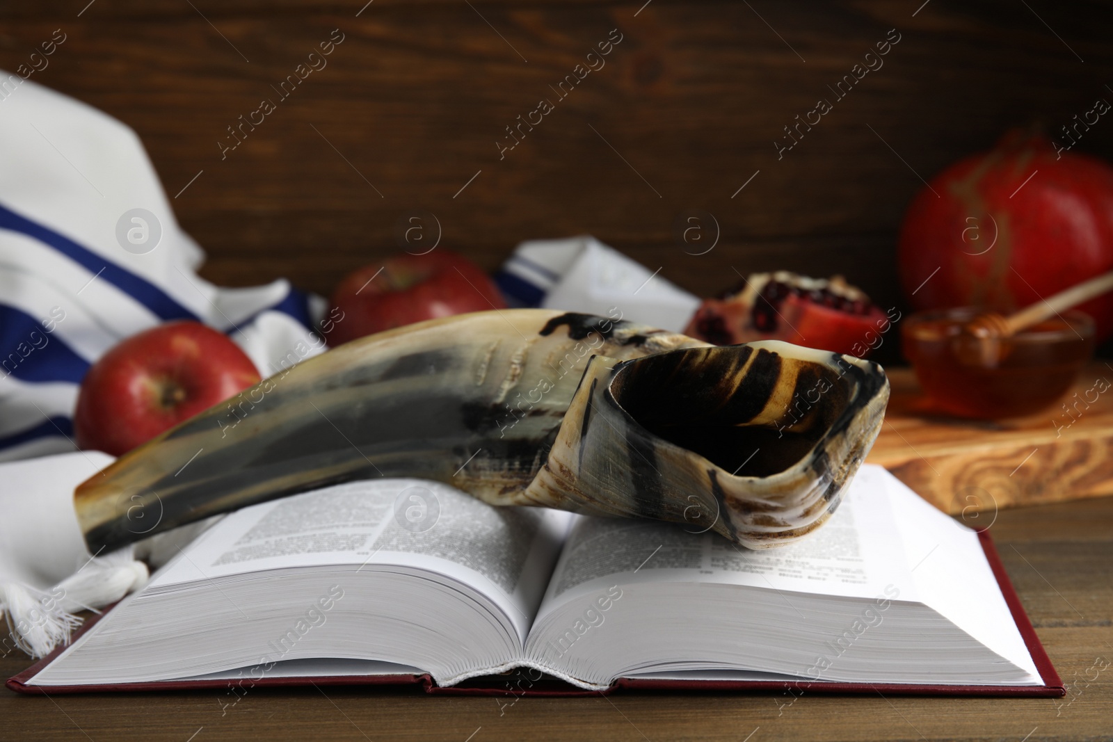 Photo of Shofar and open Torah on wooden table, closeup. Rosh Hashanah celebration