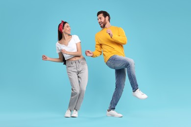 Photo of Happy couple dancing together on light blue background