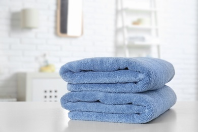 Photo of Stack of fresh towels on table in bathroom. Space for text