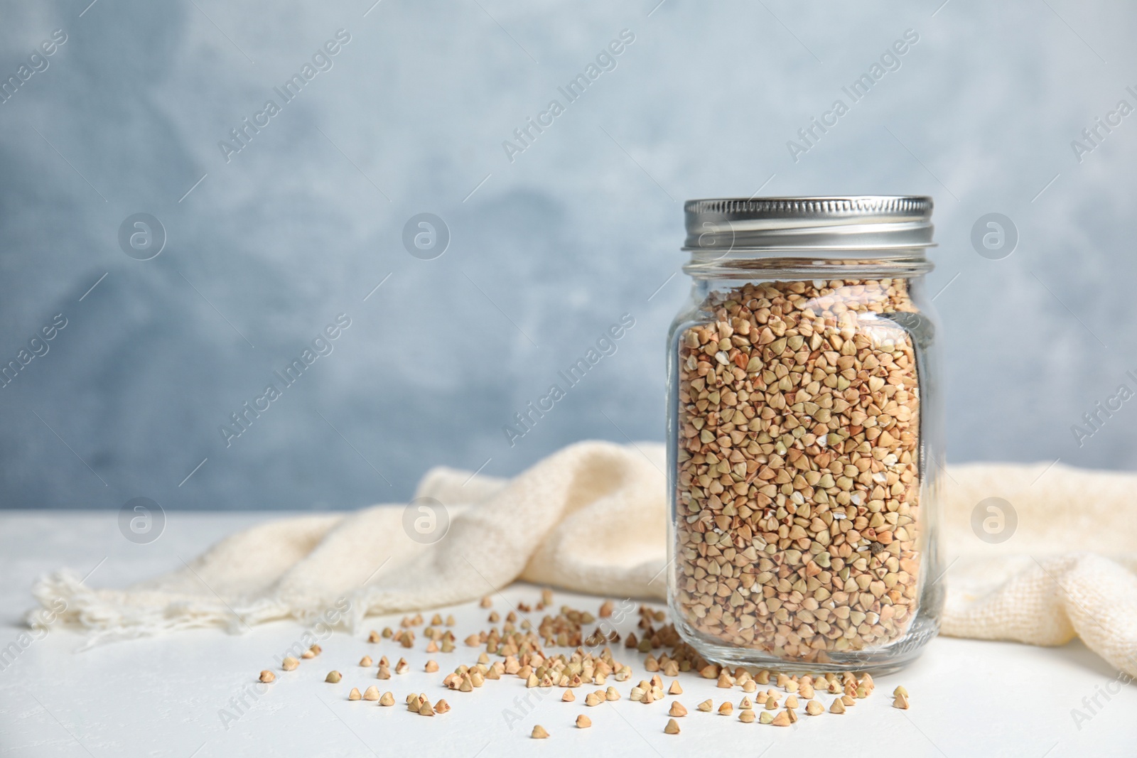 Photo of Jar with green buckwheat on white table. Space for text