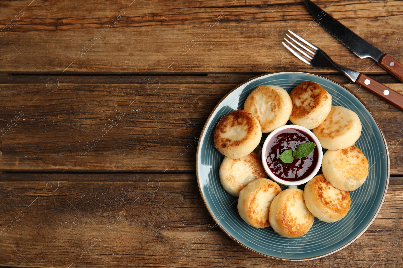 Photo of Delicious cottage cheese pancakes with jam and mint on wooden table, flat lay. Space for text