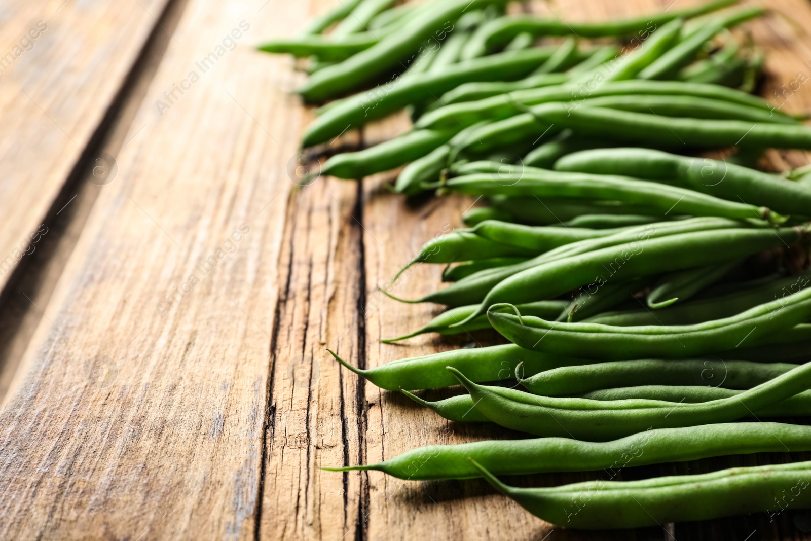 Photo of Fresh green beans on wooden table, closeup. Space for text