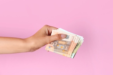Woman with Euro banknotes on pink background, closeup