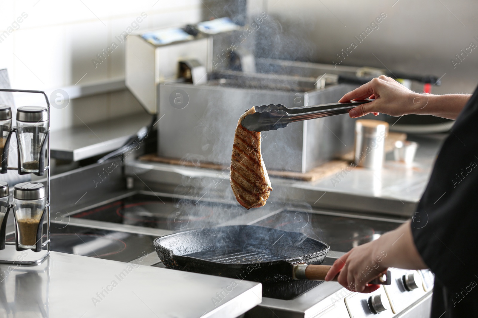 Photo of Female chef cooking chicken fillet on stove in restaurant  kitchen, closeup