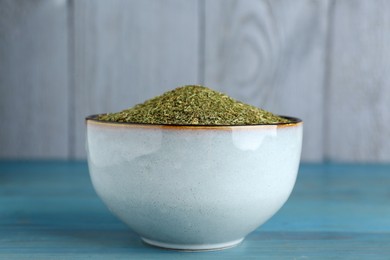 Photo of Dried dill in bowl on turquoise wooden table, closeup