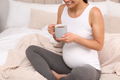 Pregnant woman drinking tea at home, closeup