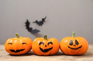 Photo of Pumpkins with scary faces near decorative bats on grey background, space for text. Happy Halloween