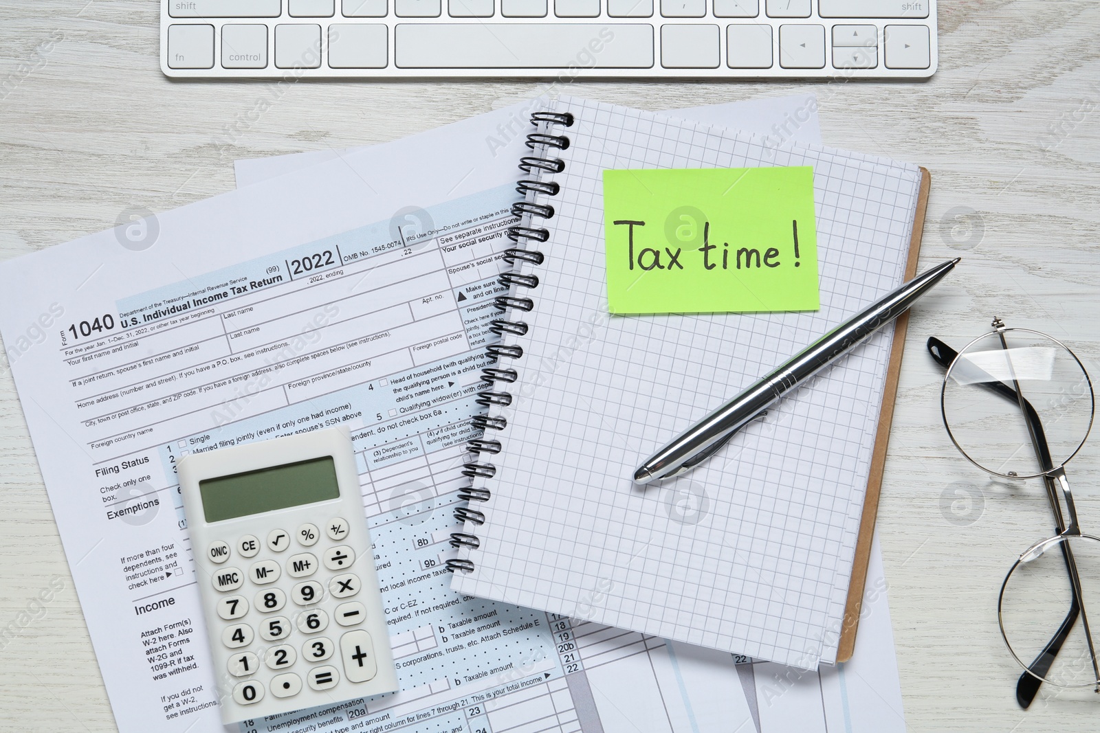 Photo of Reminder note with words Tax Time, documents, keyboard, glasses and calculator on white wooden table, flat lay