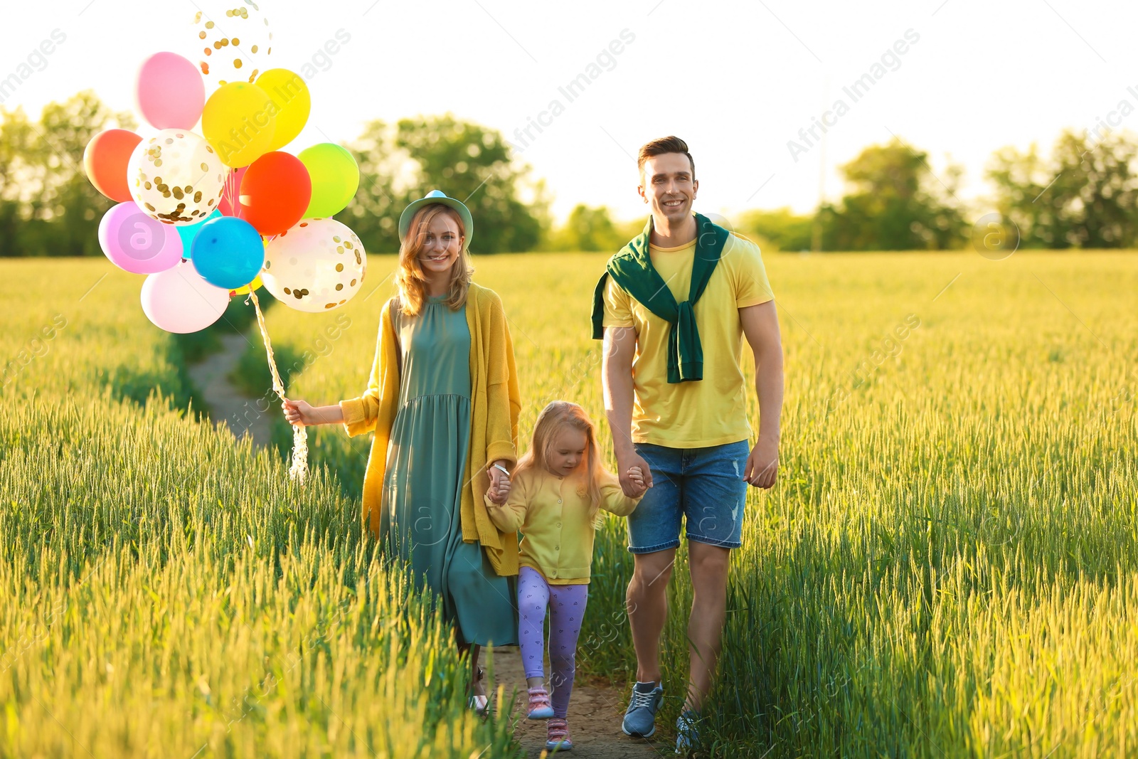 Photo of Happy family with colorful balloons in field on sunny day