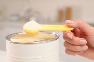 Photo of Woman with powdered infant formula indoors, closeup. Preparing baby milk