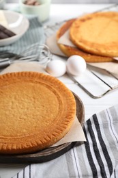 Photo of Delicious homemade sponge cake and ingredients on white table