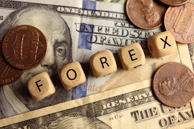 Photo of Word Forex made of wooden cubes with letters and coins on banknotes, flat lay