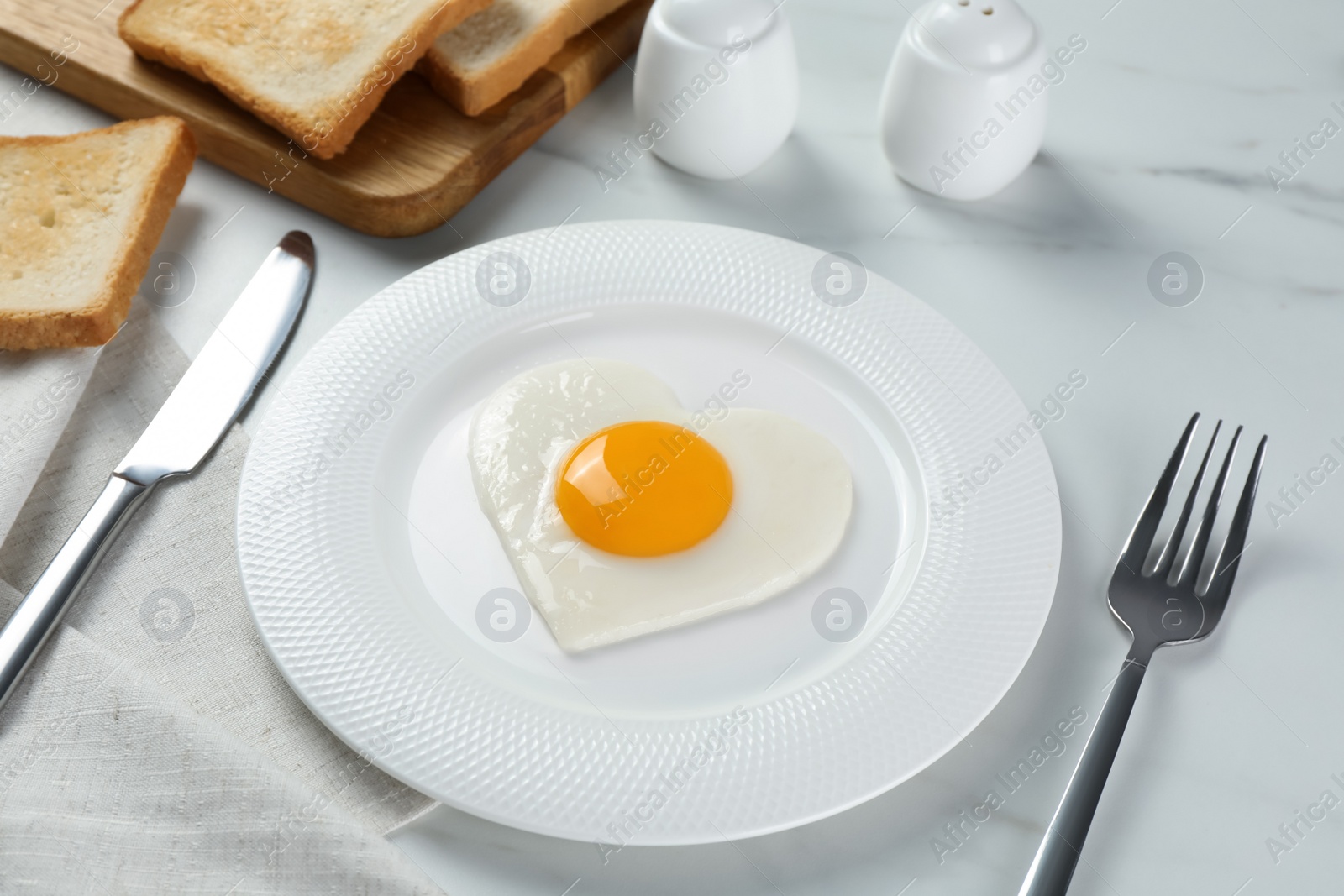 Photo of Romantic breakfast with heart shaped fried egg served on white marble table