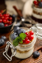 Photo of Delicious yogurt parfait with fresh berries and mint on wooden table, closeup