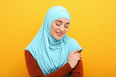 Photo of Portrait of Muslim woman in hijab on orange background