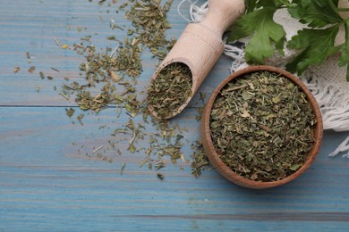 Photo of Dried parsley and fresh leaves on light blue wooden table, flat lay. Space for text