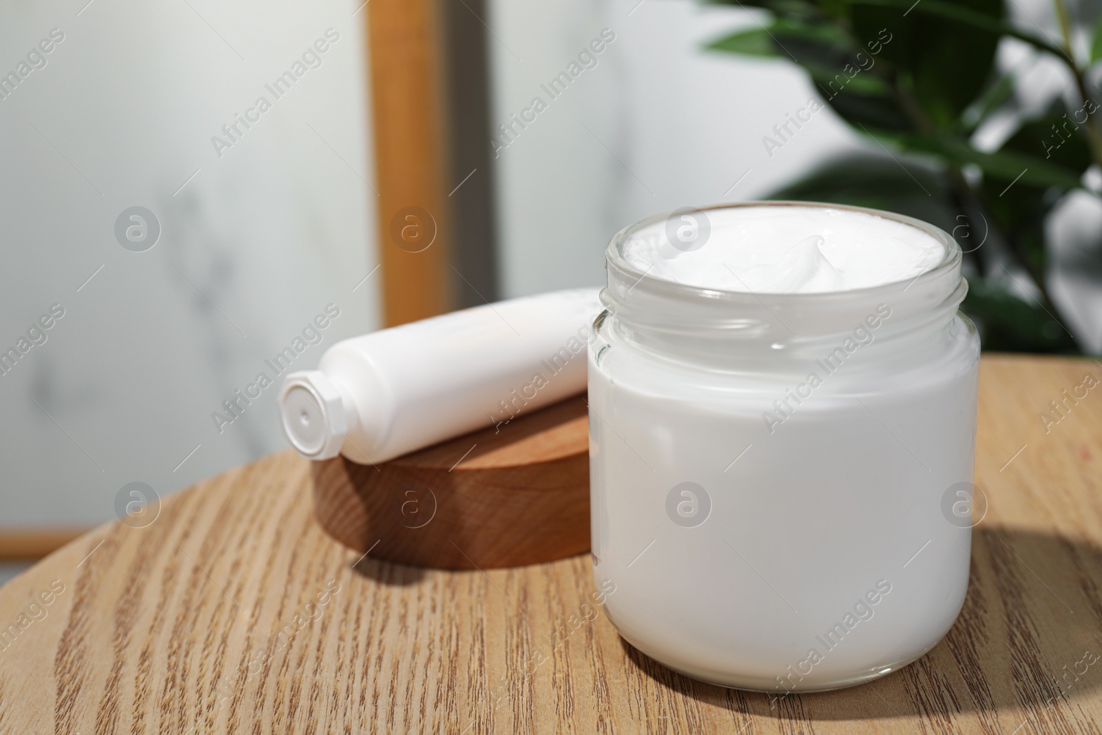 Photo of Jar and tube of hand cream on wooden table indoors, space for text