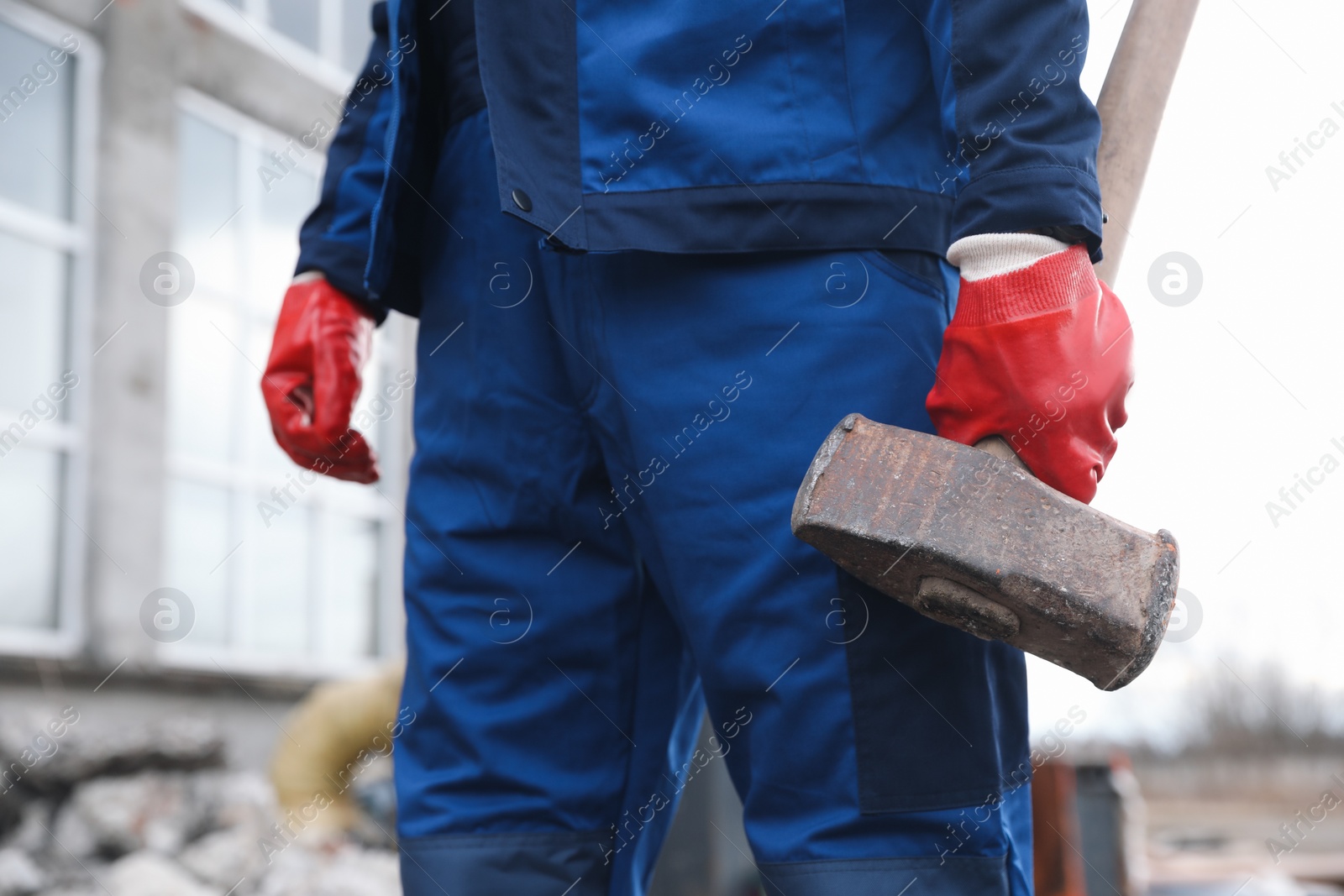 Photo of Man in uniform with sledgehammer outdoors, closeup