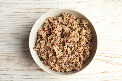 Cooked delicious quinoa in bowl on wooden table, top view