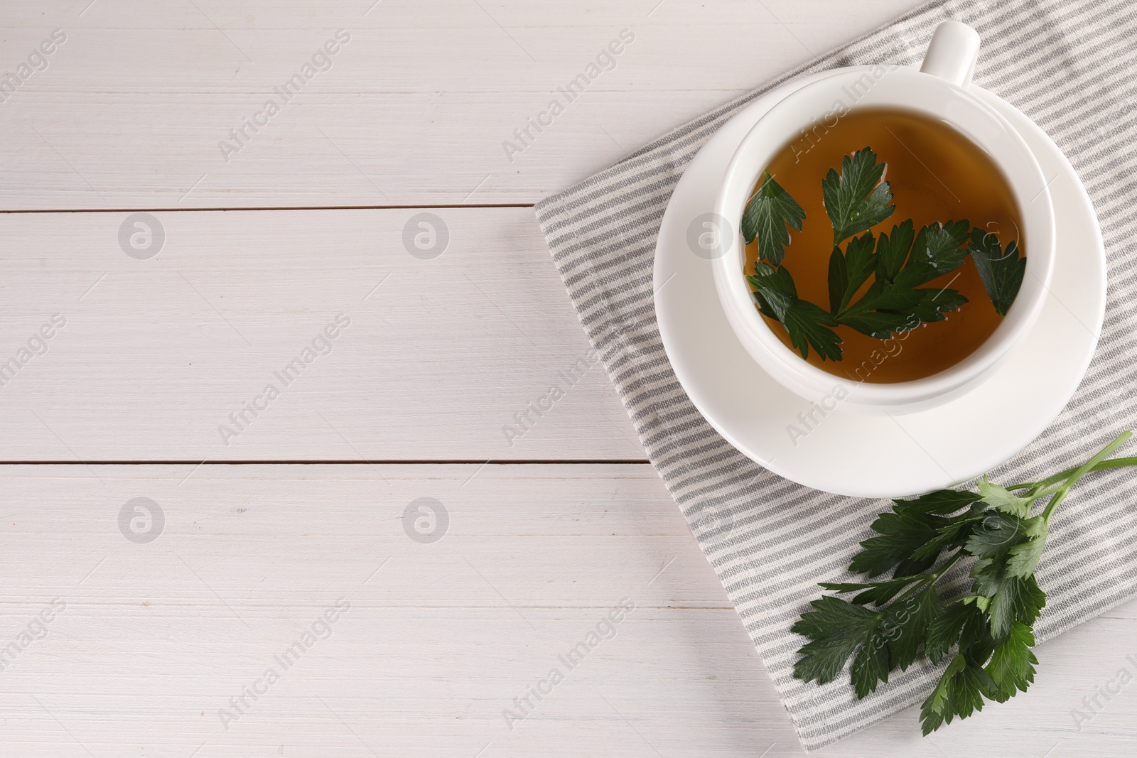 Photo of Aromatic herbal tea and fresh parsley on white wooden table, top view. Space for text