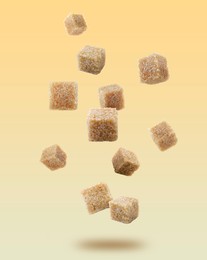 Image of Brown cane sugar cubes falling on golden gradient background