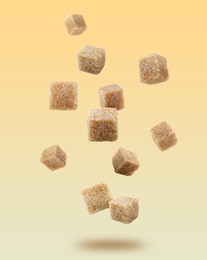 Brown cane sugar cubes falling on golden gradient background