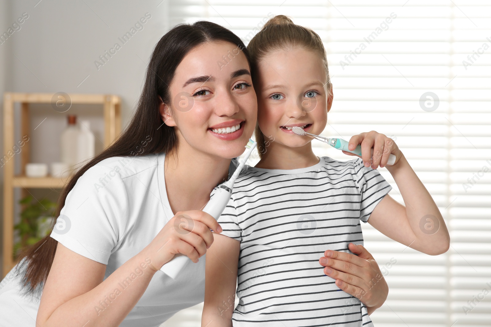 Photo of Mother and her daughter brushing teeth together in bathroom