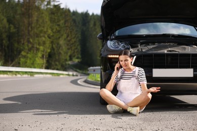 Photo of Stressed woman talking on smartphone near broken car outdoors, space for text