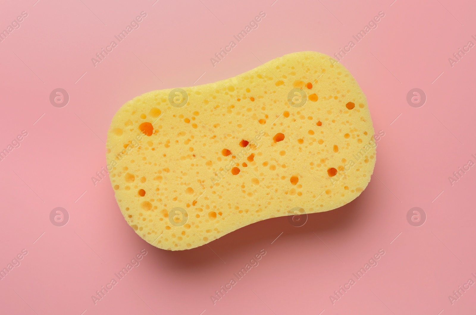 Photo of New yellow sponge on pink background, top view