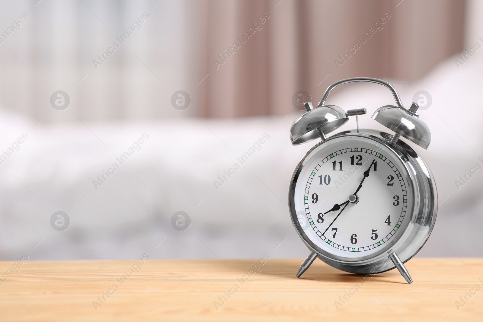 Photo of Silver alarm clock on wooden table indoors. Space for text