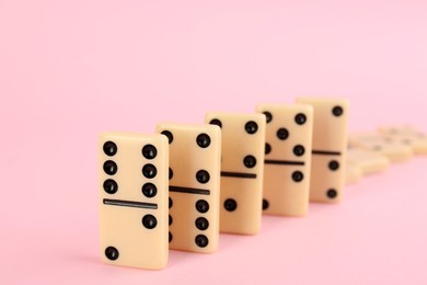 Photo of White domino tiles falling on pink background