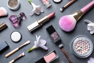 Photo of Many different makeup products and spring flowers on color background, flat lay