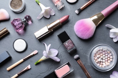 Many different makeup products and spring flowers on color background, flat lay