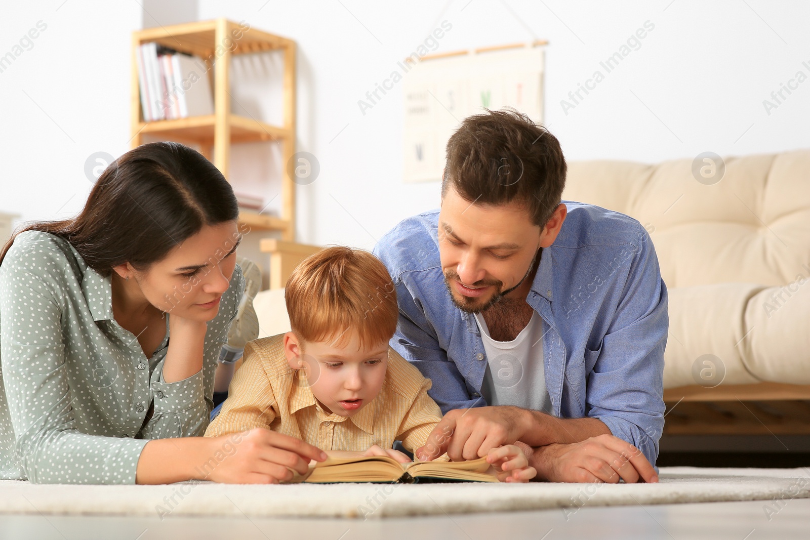 Photo of Happy family reading book together on floor in living room at home