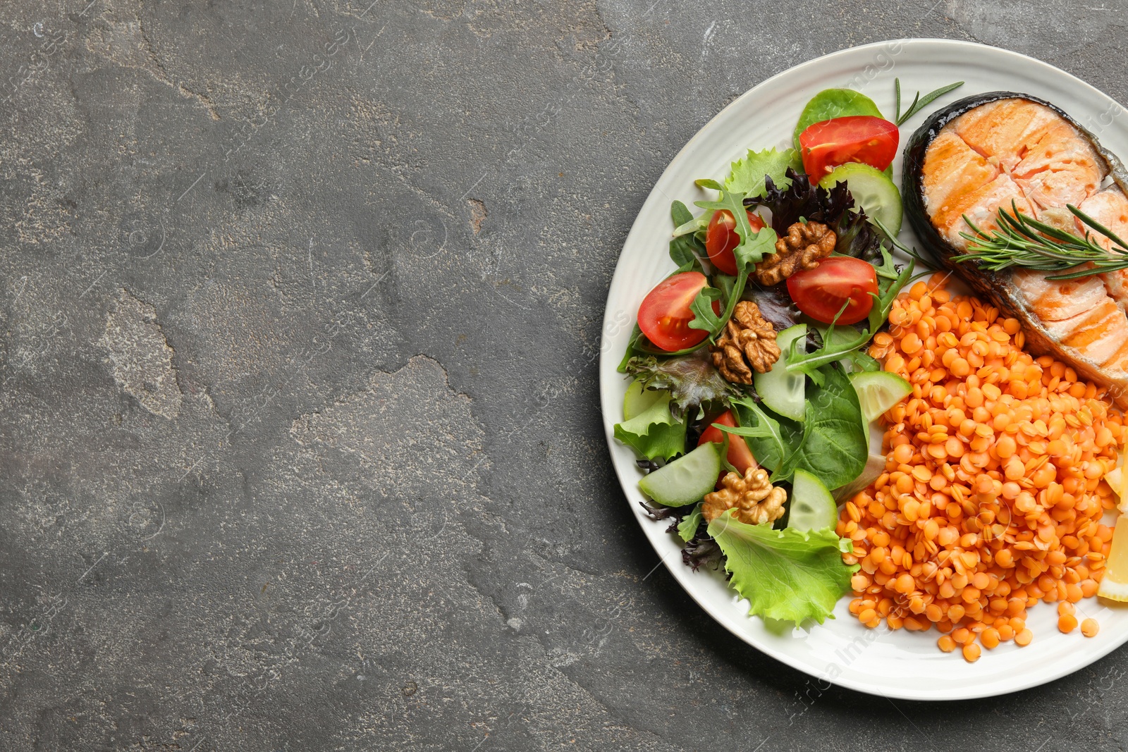 Photo of Plate with healthy food high in vegetable fats on grey textured table, top view. Space for text