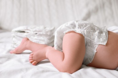 Photo of Little baby in diaper lying on bed, closeup