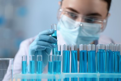 Scientist holding test tube with sample in laboratory, selective focus