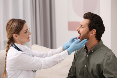 Doctor in gloves examining man`s oral cavity indoors