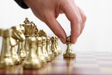 Photo of Man moving chess piece on board against white background, closeup