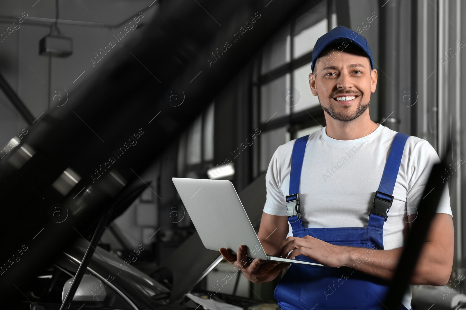 Photo of Mechanic with laptop doing car diagnostic at automobile repair shop