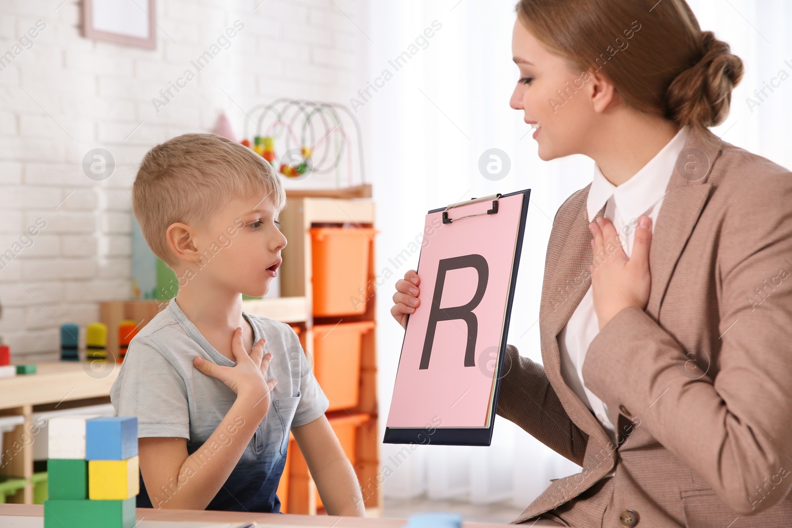 Photo of Speech therapist working with little boy in office