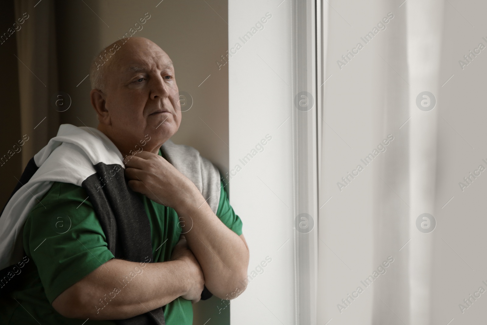 Photo of Portrait of elderly man near window indoors. Space for text