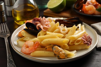Photo of Delicious pasta with seafood served on wooden table, closeup