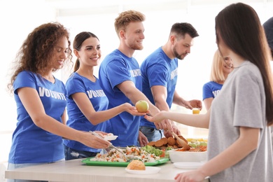 Volunteers serving food to poor people indoors