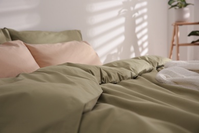 Photo of Large bed with soft blanket indoors, closeup