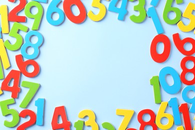 Photo of Frame made of colorful numbers on light blue background, flat lay. Space for text