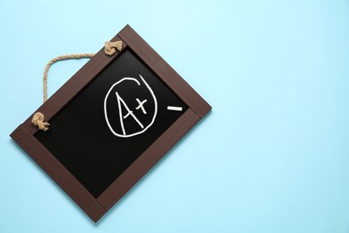 Image of School grade. Small blackboard with chalked letter A and plus symbol on light blue background