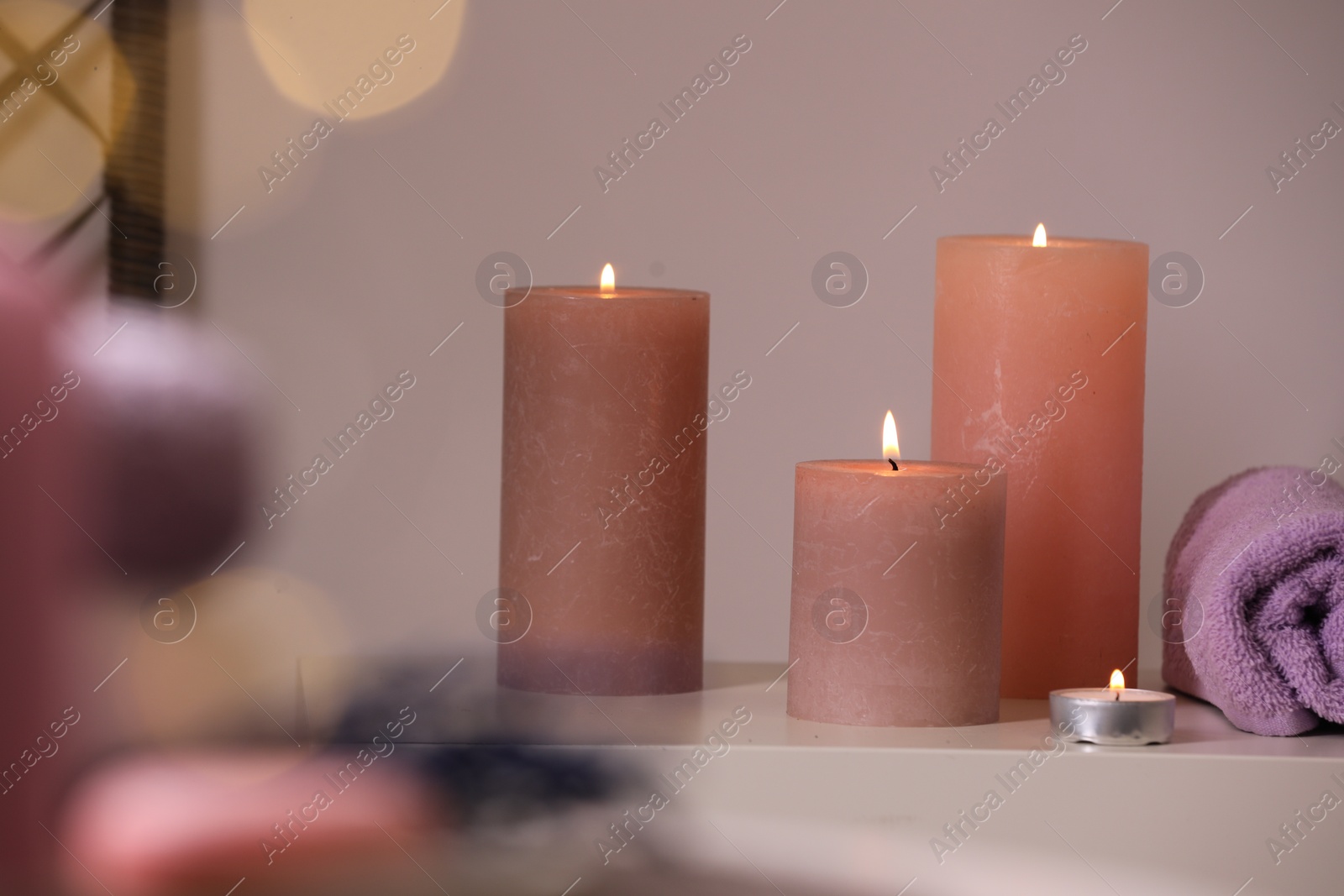 Photo of Spa composition. Burning candles and towel on white table